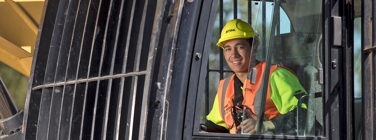 Young man driving inside cab of forestry digger